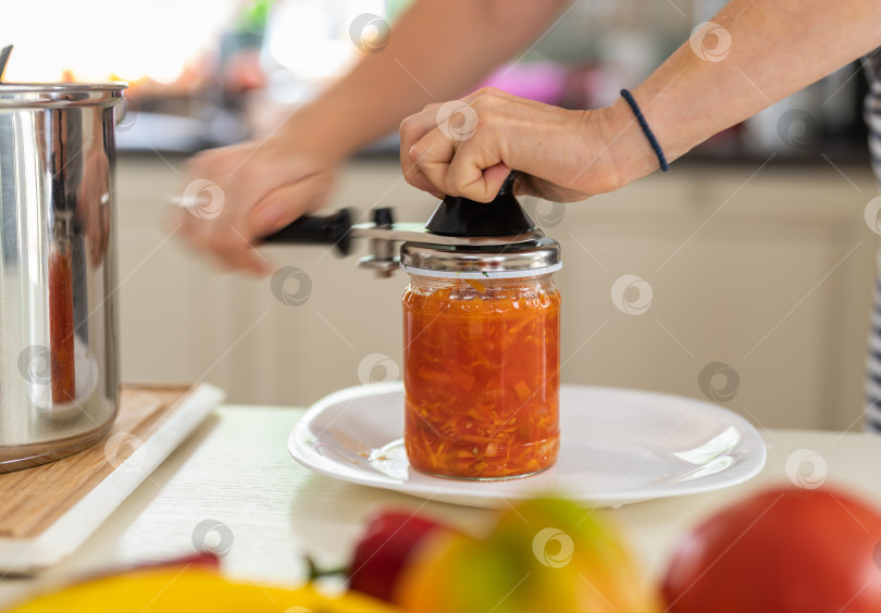 Скачать Домашнее консервирование овощей. Женщина крупным планом консервирует овощной салат в стеклянной банке фотосток Ozero