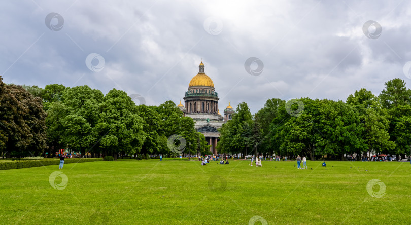 Скачать Исаакиевская площадь в Санкт-Петербурге, на лужайке которой отдыхают люди на фоне собора Святого Петра. Исаакиевский собор фотосток Ozero