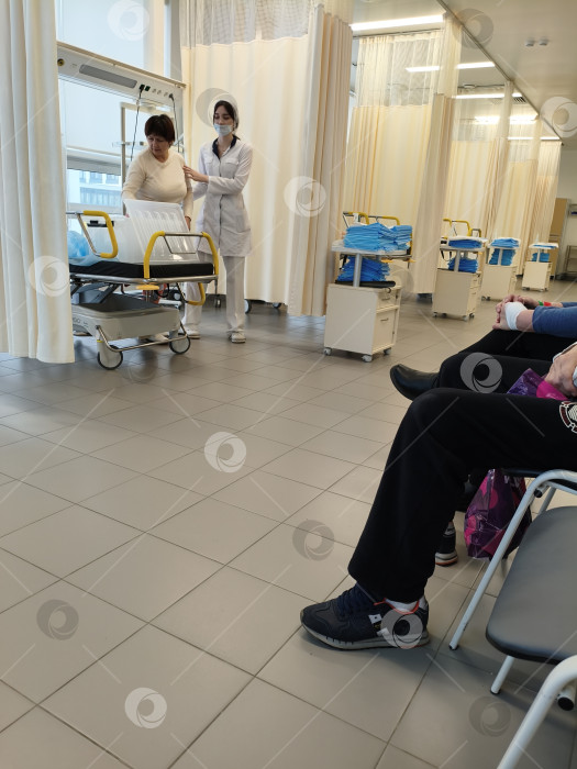 Скачать Медработник в белом халате помогает пациентке в  медицинском кабинете после обследования ЖКТ. Москва, Коммунарка, 1.03.2026г фотосток Ozero