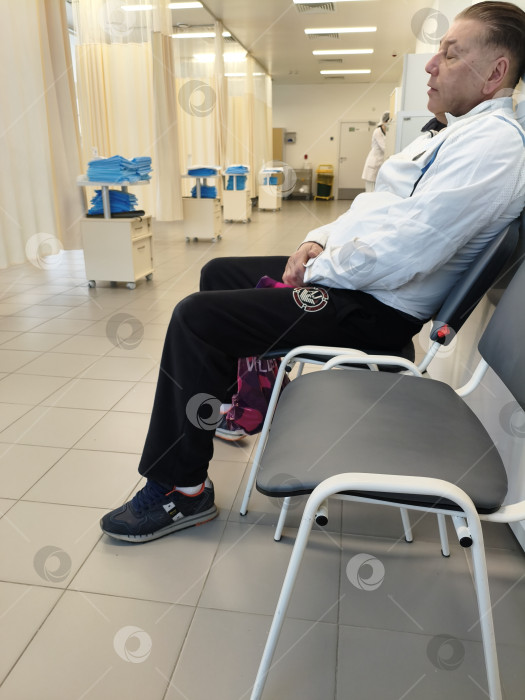 Скачать Мужчина в медицинском учреждении сидит на стуле процедурного кабинета после обследования ЖКТ. Москва, Коммунарка, 1.03.2026г фотосток Ozero