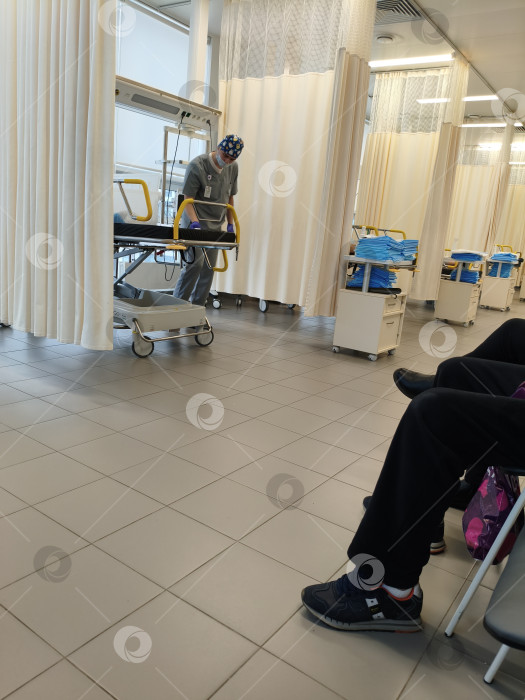 Скачать Медработник в спецодежде и маске дезинфицирует каталку в процедурном помещении, медицинского центра. Москва, Коммунарка, 1.03.2026г фотосток Ozero