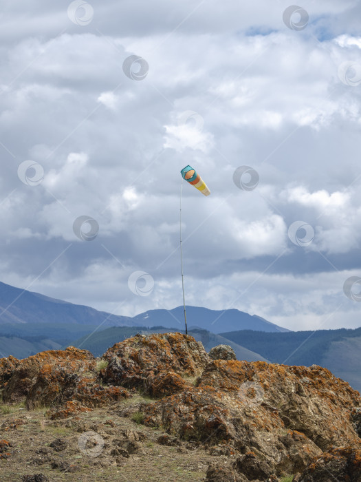 Скачать Флюгер, обозначающий ветер на фоне голубых гор. фотосток Ozero