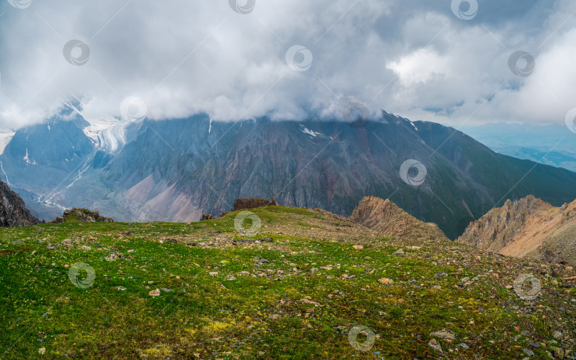 Скачать Облака спускаются на долину с гор. Атмосферные большие снежные горные вершины в облачном небе. фотосток Ozero