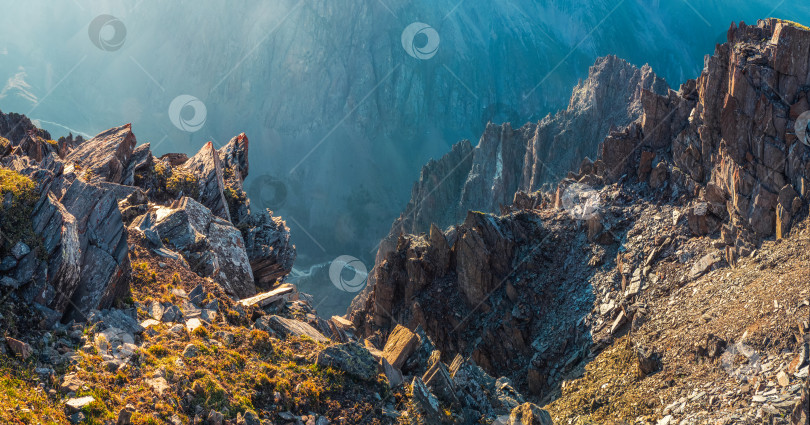 Скачать Панорамный вид на опасный кулуар. Красочный солнечный пейзаж с утесами, большими скалистыми горами и эпическим глубоким ущельем. фотосток Ozero