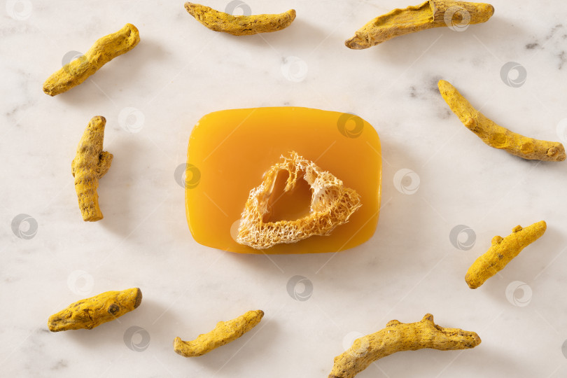 Скачать Кусочек мыла ручной работы с куркумой на белом мраморном фоне. фотосток Ozero
