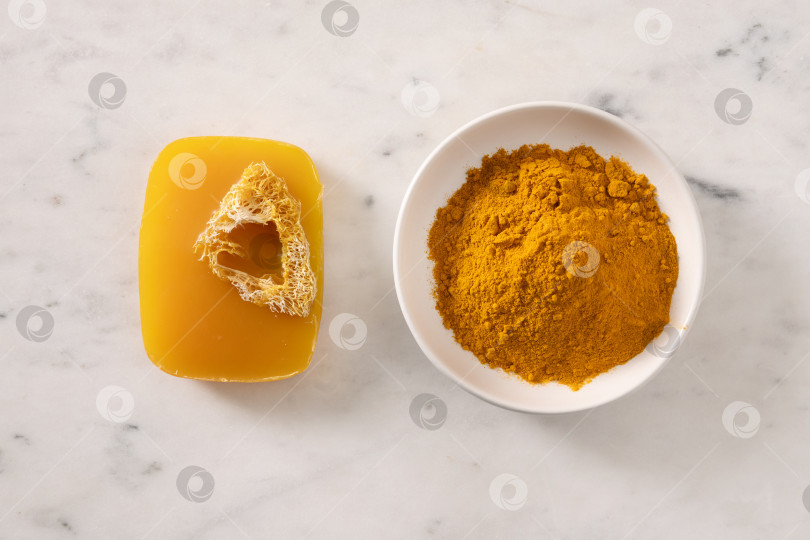 Скачать Кусочек мыла ручной работы с куркумой на белом мраморном фоне. фотосток Ozero
