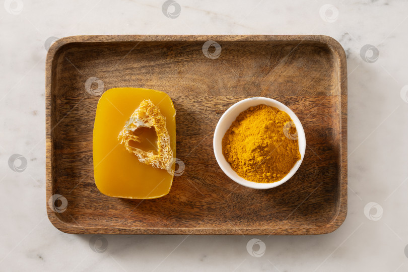 Скачать Кусочек мыла ручной работы с куркумой на белом мраморном фоне. фотосток Ozero
