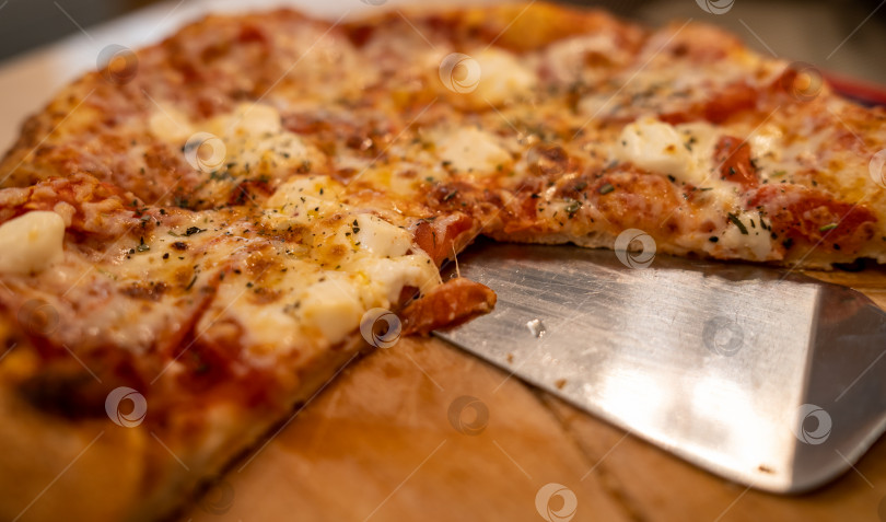 Скачать горячая, сочная и вкусная пицца лежит на деревянной тарелке крупным планом фотосток Ozero