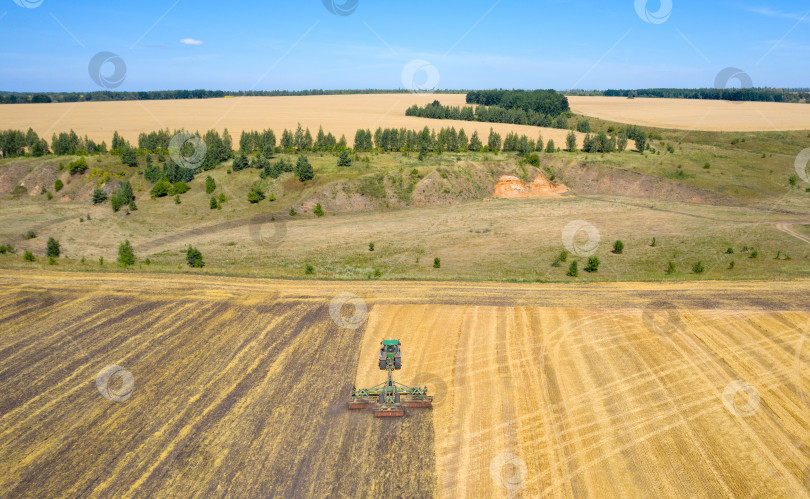 Скачать аэрофотоснимок: трактор вспахивает поле после уборки зерновых культур фотосток Ozero