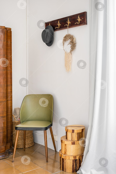 Скачать Прихожая с белым сеном в атмосферном стиле бохо. На стене - резная вешалка для верхней одежды и мужская черная шляпа. Красивый зеленый деревянный стул. Коробки на полу для украшения. фотосток Ozero