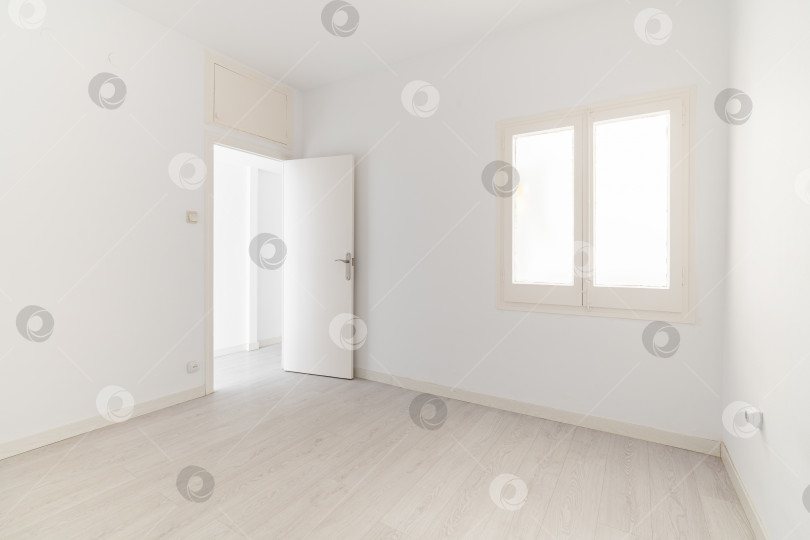 Скачать Вид на пустую белую светлую комнату с окном без мебели после покраски и ремонта с деревянным полом и плинтусами. Концепция красивого лаконичного интерьера для различных вдохновляющих идей фотосток Ozero