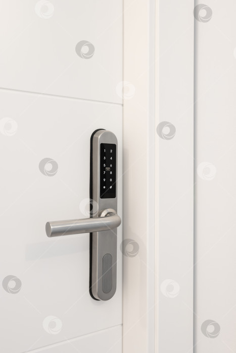Скачать Входная белая деревянная дверь с электронным замком для безопасности квартиры. На замке есть кнопки с цифрами для ввода кода. Хромированный металлический замок. фотосток Ozero
