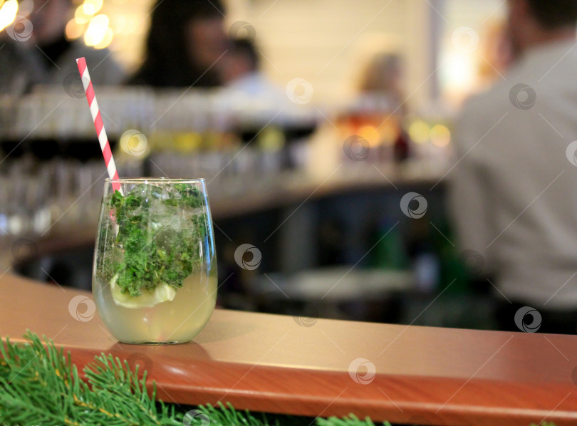 Скачать Бокал коктейля мохито на деревянном столе с полосатой красно-белой соломинкой, льдом и листьями мяты фотосток Ozero