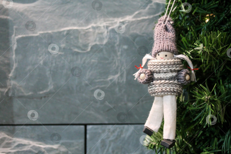 Скачать Ветки рождественской ели украшены игрушечной фигуркой девочки, связанной крючком. фотосток Ozero