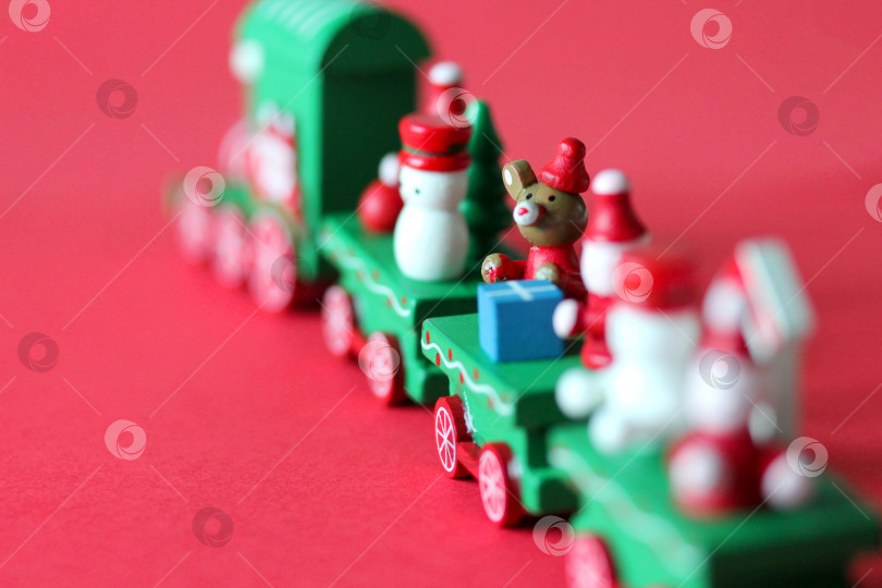 Скачать Зеленый праздничный деревянный поезд уезжает на красном фоне с пространством для копирования фотосток Ozero