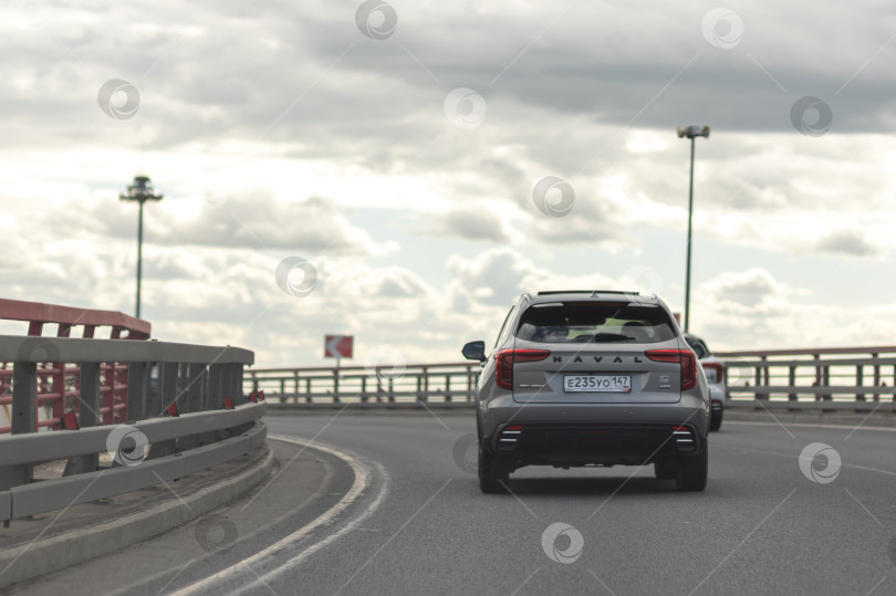Скачать Китайский внедорожник Haval на шоссе под Санкт-Петербургом, июнь 2026 года, современный, темного цвета, быстро едет под пасмурным летним небом. фотосток Ozero