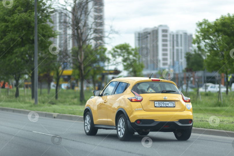 Скачать Россия, Санкт-Петербург, июнь 2026 года: Желтый Nissan Beetle едет по городской дороге под голубым небом с белыми облаками. фотосток Ozero