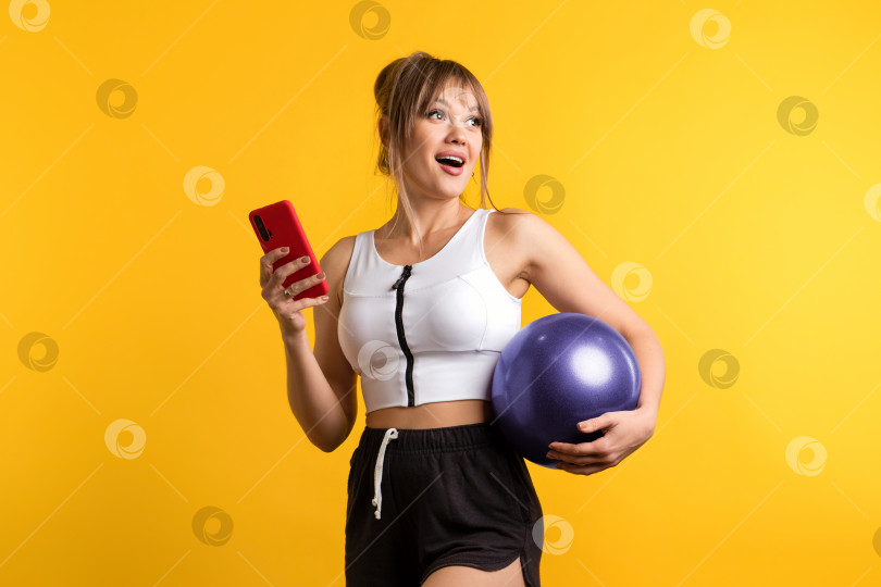 Скачать Женщина с гимнастическим мячом и смартфоном фотосток Ozero