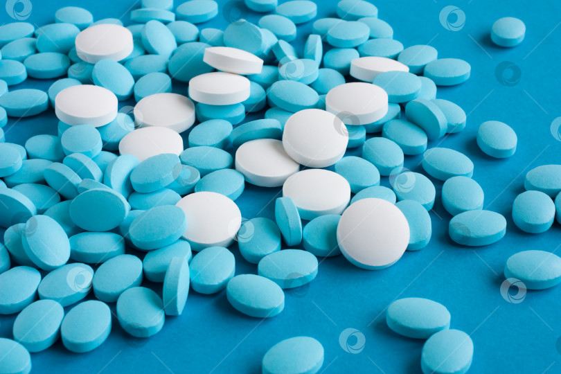 Скачать Белые и светло-голубые таблетки на синем фоне. Медицина и здоровье фотосток Ozero