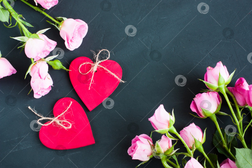 Скачать Маленькие розовые розы и два деревянных красных сердечка на темно-сером фоне. Композиция ко дню Святого Валентина, выборочный фокус. фотосток Ozero
