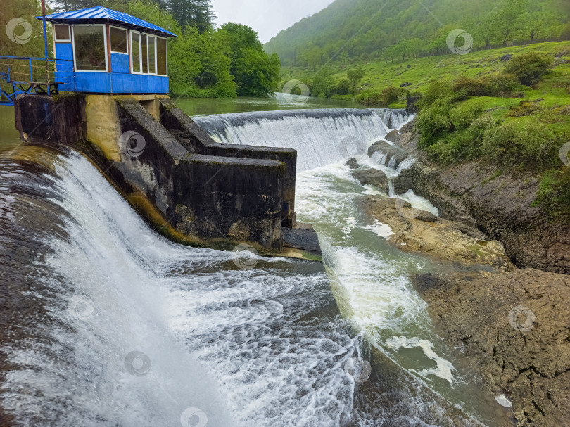 Скачать Бурный водопад низвергается каскадами по каменному сооружению плотины фотосток Ozero