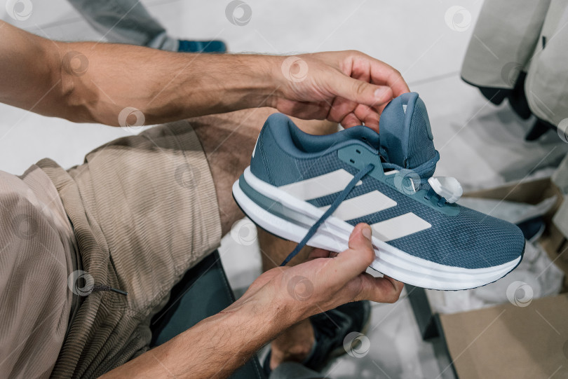 Скачать Бар, Черногория, 20 июня 2026 года, Мужчина выбирает кроссовки Adidas в спортивном торговом центре фотосток Ozero