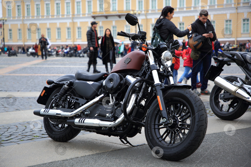 Скачать Парковка мотоцикла Harley-Davidson на городской площади среди пешеходов и мотоциклистов фотосток Ozero
