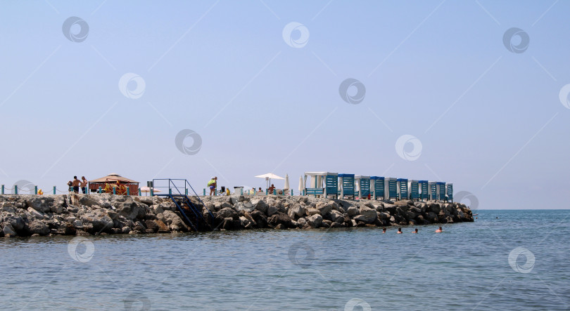 Скачать Пляж с кабинками на скалистом берегу фотосток Ozero