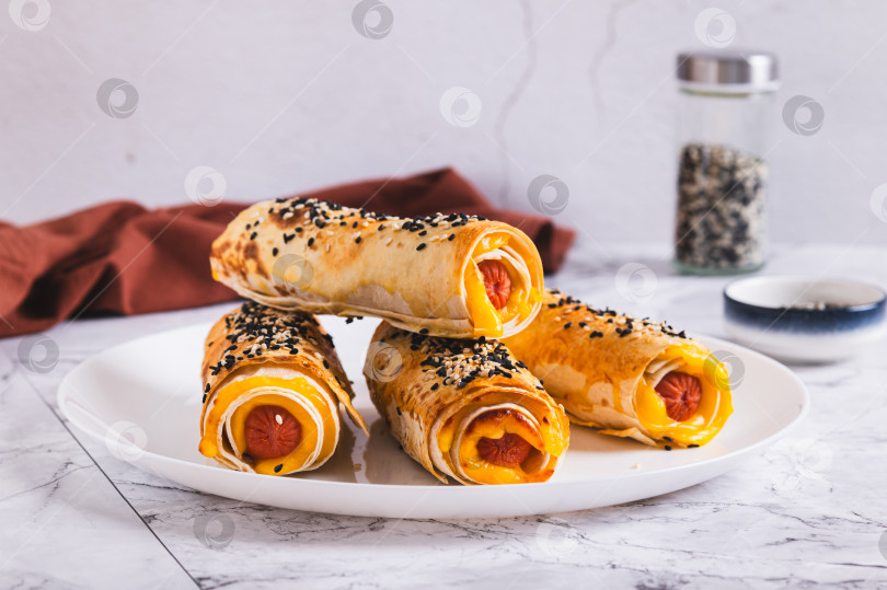 Скачать Сосиски с сыром, запеченные в лаваше на тарелке, подаются на стол фотосток Ozero