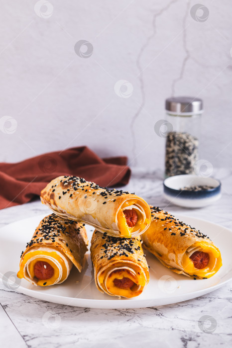 Скачать Сосиски с сыром, запеченные в лаваше, на тарелке на столе, вид сверху фотосток Ozero