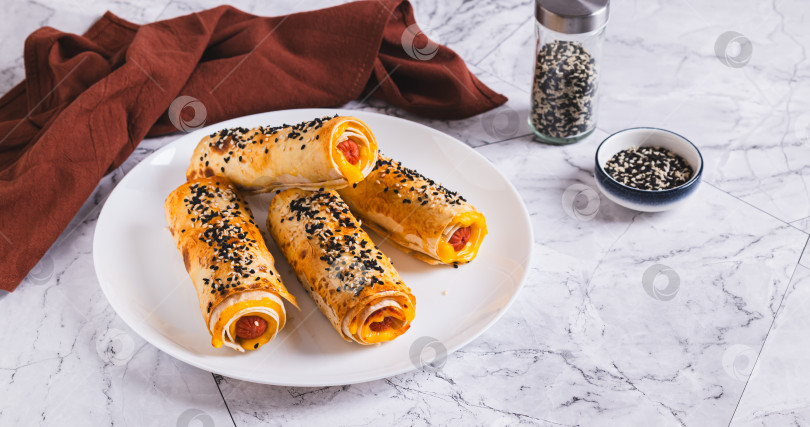 Скачать Сосиски с сыром, запеченные в лаваше, на тарелке на столе веб-баннер фотосток Ozero