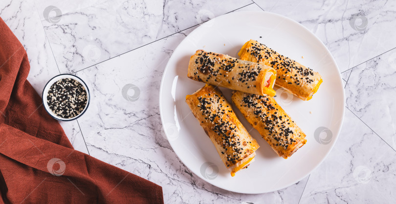 Скачать Роллы на гриле с колбасками, сыром, лавашом и кунжутом на тарелке на столешнице посмотреть веб-баннер фотосток Ozero