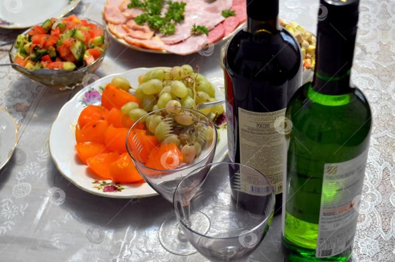 Скачать Салаты, закуски, фрукты, вино красное и белое и два бокала на столе фотосток Ozero