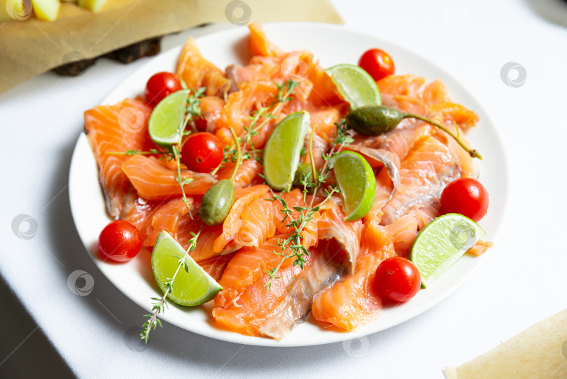 Скачать Карпаччо из лосося с помидорами, оливками и лаймом на белой тарелке фотосток Ozero
