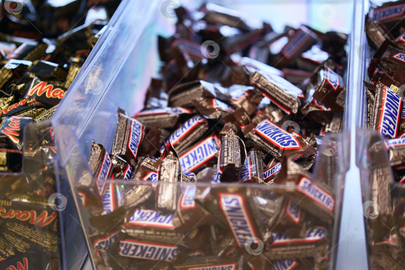 Скачать Тюмень, Россия-20 марта 2026 года: Шоколадные конфеты Snickers с небольшой глубиной резкости, подчеркивающие культовый логотип фотосток Ozero