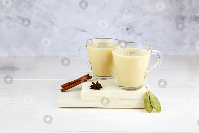 Скачать Две стеклянные чашки горячего чая с молоком и специями на светлом фоне. Традиционный индийский чай масала. фотосток Ozero