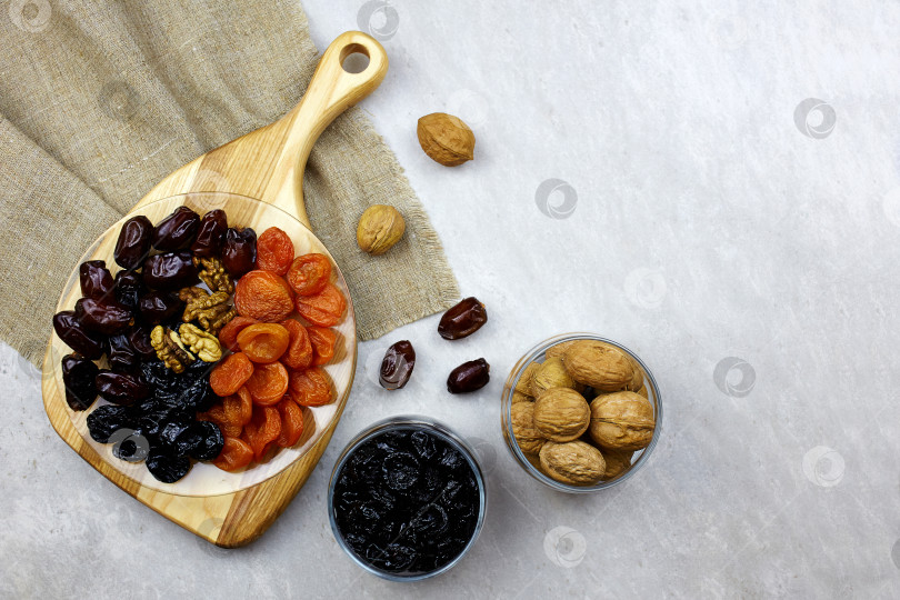 Скачать Продукты для Рамадана: финики, орехи, курага, чернослив на фоне светлого дерева, вид сверху. фотосток Ozero