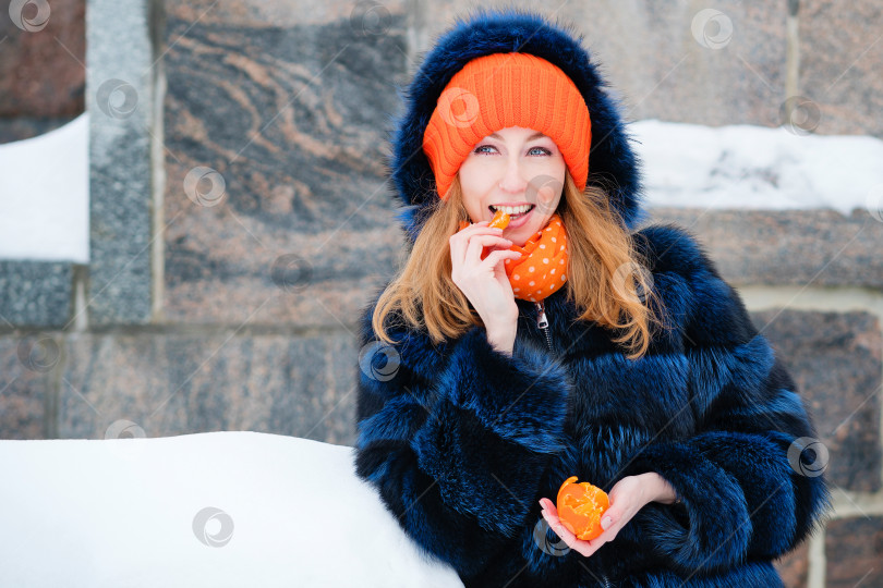 Скачать Молодая женщина наслаждается мандарином фотосток Ozero