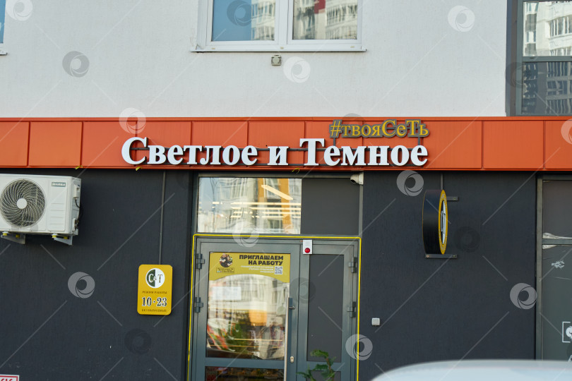Скачать Тюмень, Россия - 6 сентября 2026 года: Крупный план освещенной вывески магазина "Светлое и Темное" на темно-серой стене у входа в здание. фотосток Ozero