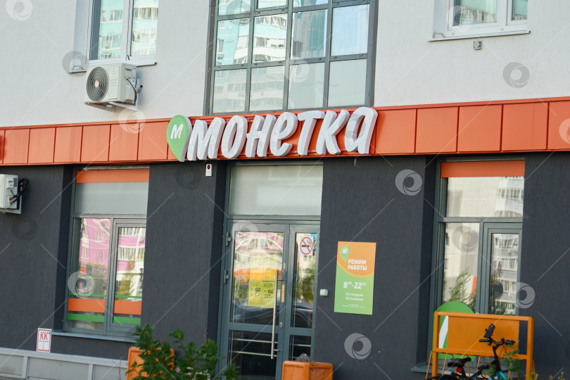 Скачать Тюмень, Россия - 6 сентября 2026 года: Вид спереди на вход в продуктовый магазин "Монетка" с вывеской на оранжевом фоне на первом этаже жилого комплекса фотосток Ozero