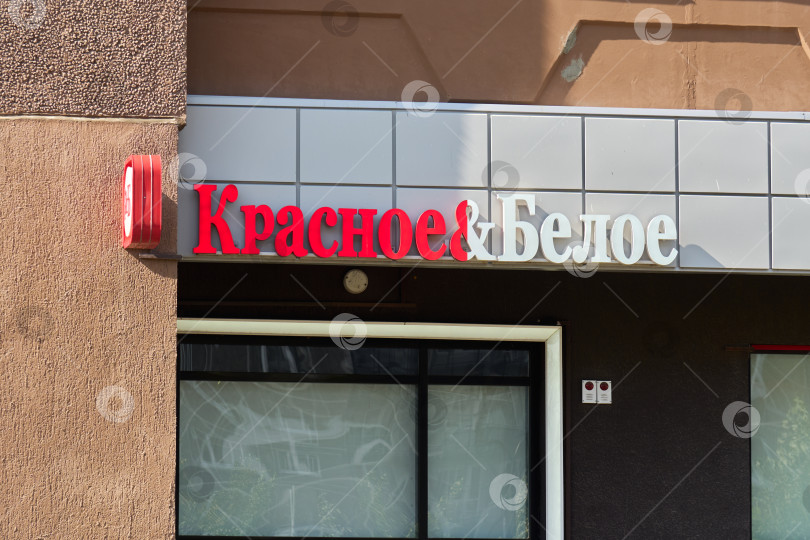 Скачать Тюмень, Россия - 6 сентября 2026 года: Красно-белая вывеска сети алкогольных и продуктовых магазинов "Красное и Белое" на здании жилого дома фотосток Ozero