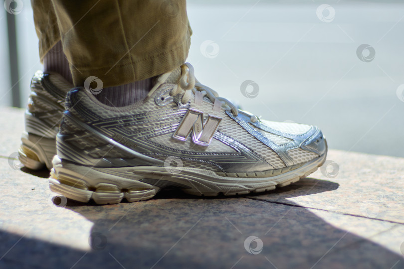 Скачать Тюмень, Россия - 10 июля 2026 года: Кроссовки New Balance 1906R для бега на открытом воздухе с брюками цвета хаки. Иллюстративная редакционная фотография современной уличной моды. фотосток Ozero