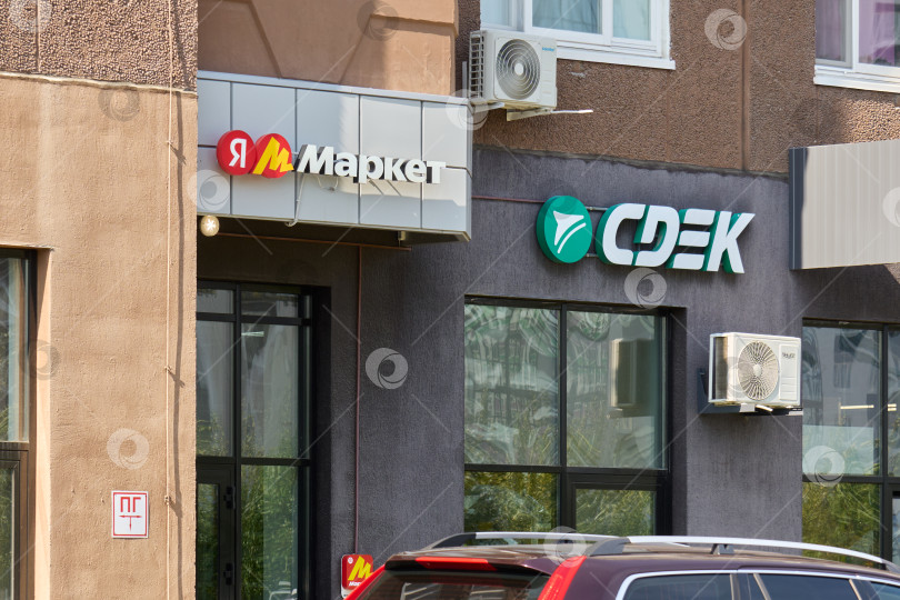 Скачать Тюмень, Россия - 6 сентября 2026 года: Вывески на внешней витрине магазина Яндекс Маркет и пункта выдачи CDEK на фасаде современного жилого здания фотосток Ozero