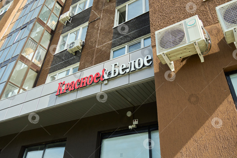 Скачать Тюмень, Россия - 6 сентября 2026 года: Перспективный вид вывески винных магазинов "Красное" и "Белое" на кириллице, установленной на фасаде современного жилого дома. фотосток Ozero