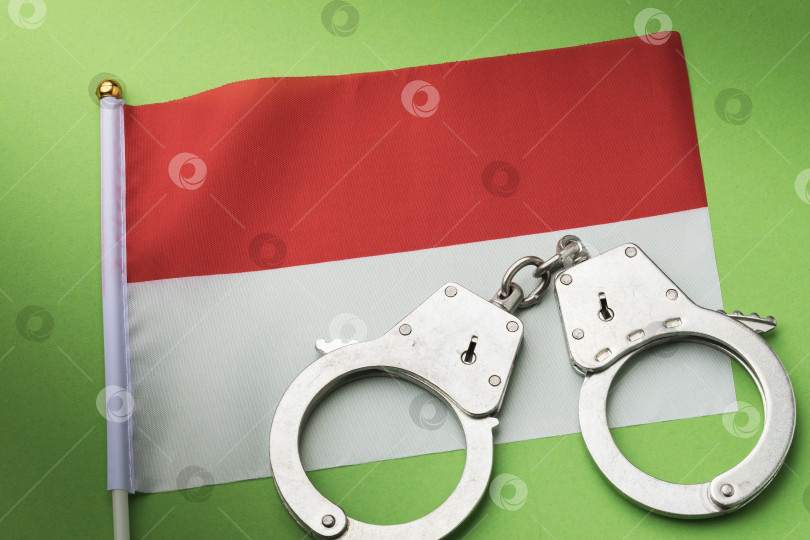 Скачать Флаг Индонезии и наручники на цветном фоне, концепция преступности в индонезийском обществе фотосток Ozero