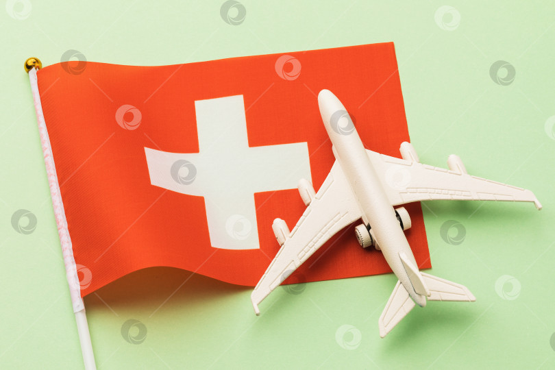 Скачать Швейцарский флаг и игрушечный самолет на цветном фоне, концепция полета в Швейцарию, вид сверху фотосток Ozero