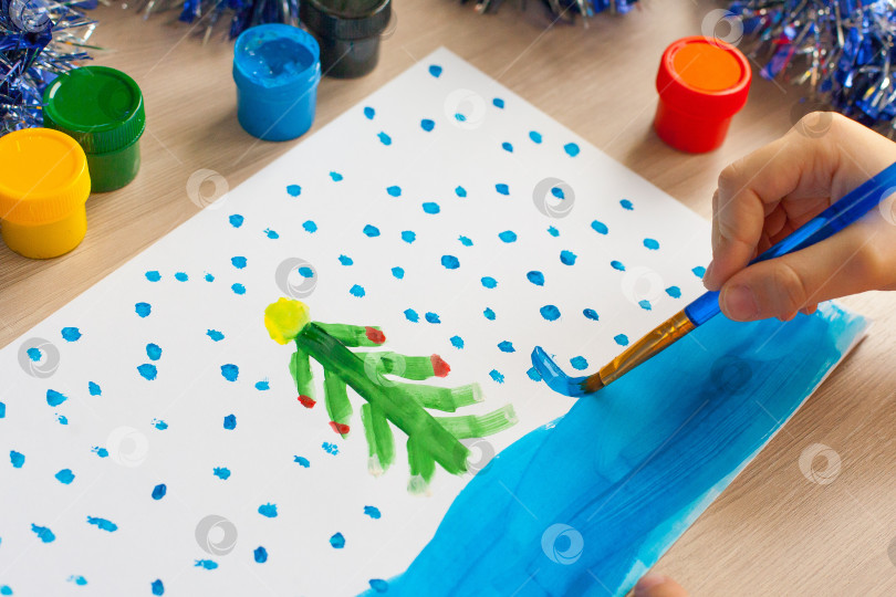 Скачать Ребенок рисует рождественскую елку. Идеи для рисования яркими красками. Рисование детей на белом фоне. Маленькая девочка рисует красками и кистями. Концепция развития детей. фотосток Ozero