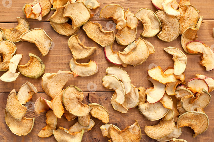Скачать крупный план сушеных яблок, нарезанных ломтиками, на деревянном столе. пищевые продукты. правильное питание. источник витаминов фотосток Ozero