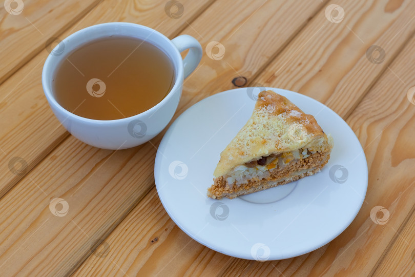 Скачать слоеный сладкий пирог на столе рядом с чашкой горячего чая. Утренний завтрак фотосток Ozero