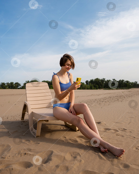 Скачать Девушка на пляже загорает, сидя на шезлонге фотосток Ozero